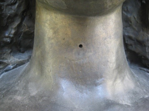 Detail of the hole on the front of the figure’s throat that was used to fasten the chinstrap